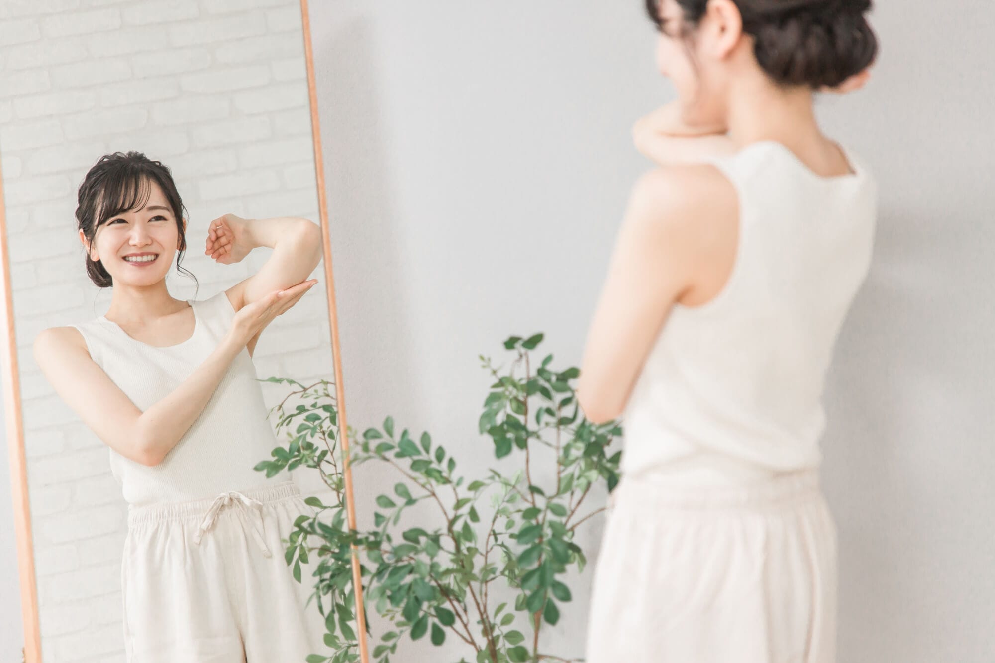 鏡で二の腕を気にしている女性