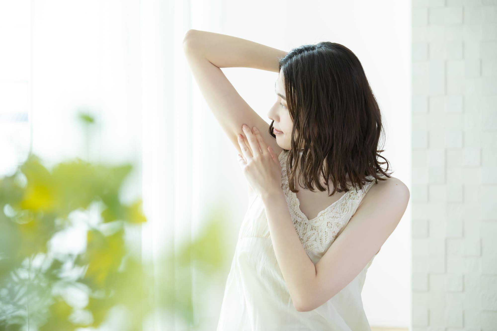 大きな窓の前で脇脱毛について考える女性