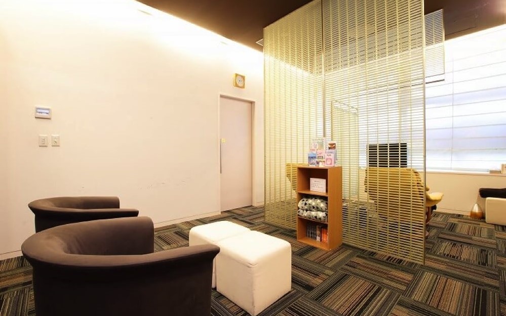 ソファ、毛布、読み物があるジュノビューティークリニック渋谷院の中待合室
